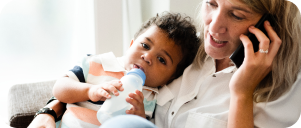 Mother feeding her baby while on the phone