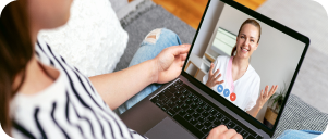 Patient having a video call with her doctor white sitting on a couch using laptop.