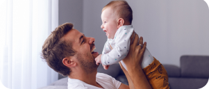 Image of dad holding up baby and smiling